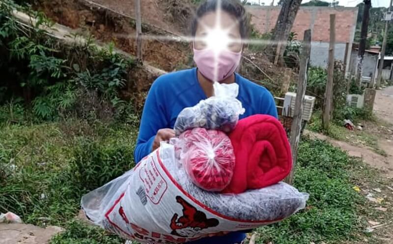 Pilha de agasalhos doados sendo organizada por voluntários.