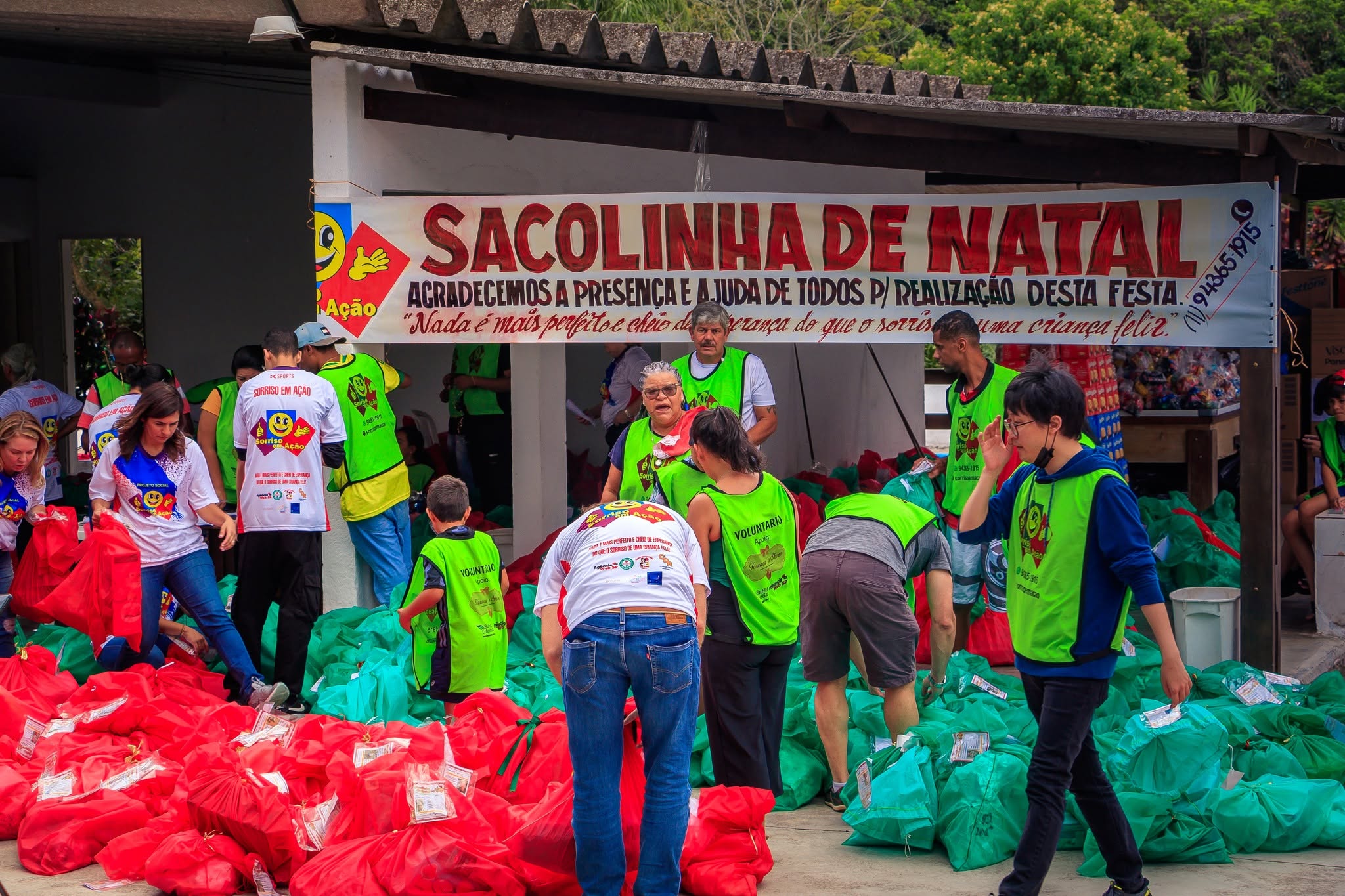 Crianças recebendo sacolinhas de Natal montadas pelo Sorriso em Ação.