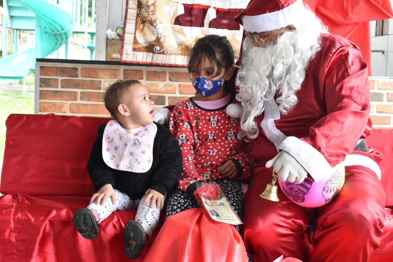 Papai Noel da Sacolinha de Natal entregando presentes para crianças atendidas pelo Sorriso em Ação.