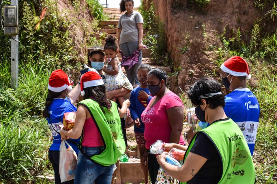 Voluntária do Sorriso em Ação, com a camiseta do projeto, carregando doações para famílias de Parelheiros.